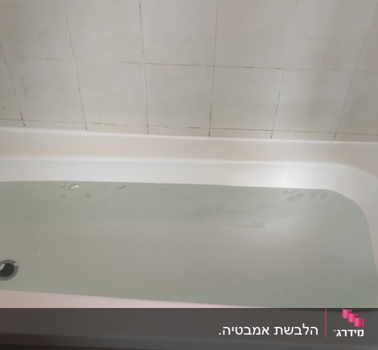 אמבטיה מלאה במים עם ברז מתכת על הקיר